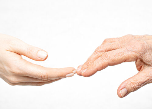Photo of a youthful hand touching an older person's hand