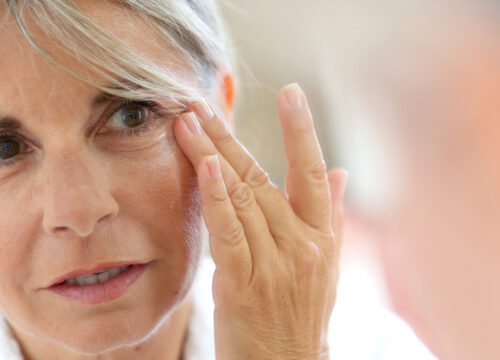Photo of an older woman touching the wrinkles around her eyes