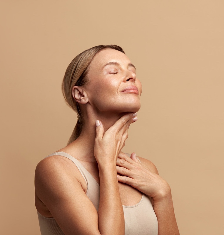 Photo of a middle-aged blonde woman touching her neckline