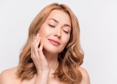Photo of woman with great skin touching her face after Sciton Clear Suite treatments